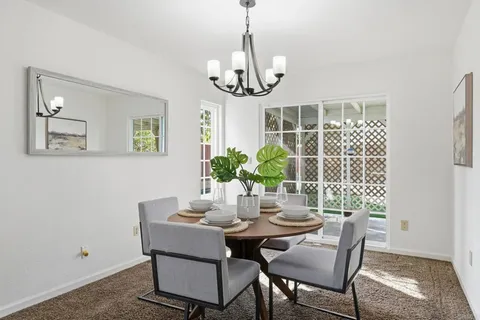 a dining room with wooden floor a chandelier a wooden table and chairs