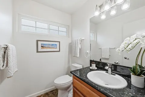 a bathroom with a granite countertop toilet sink and mirror