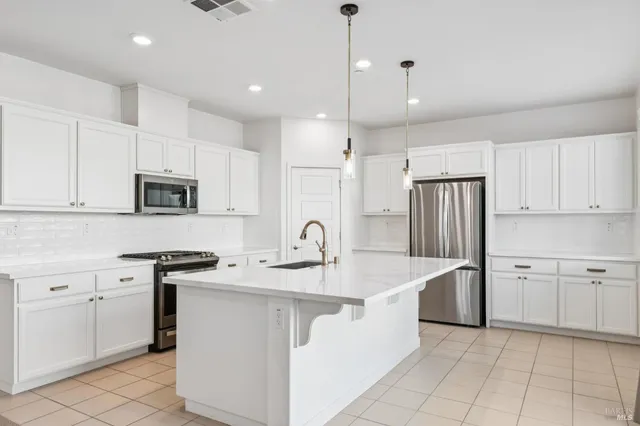 a kitchen that has a lot of white cabinets and stainless steel appliances