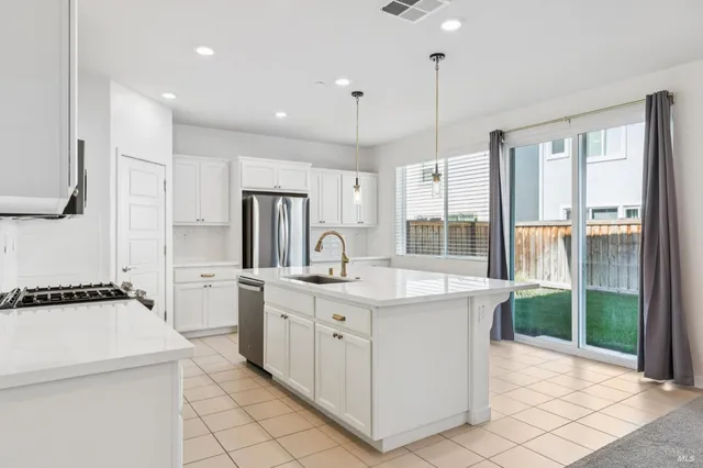 a kitchen that has a lot of white cabinets and stainless steel appliances