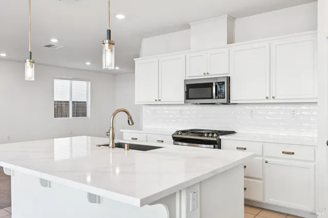 a kitchen with kitchen island a sink a stove and cabinets