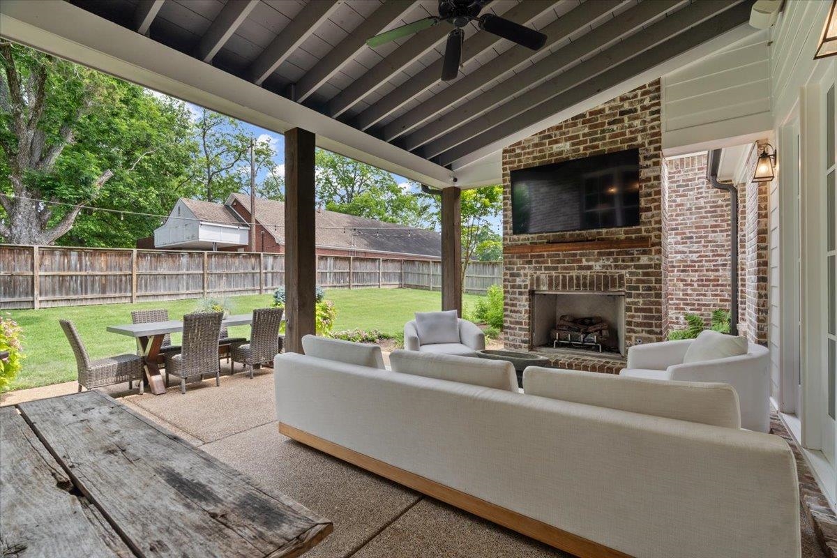 240 Burrows Road Collierville, TN 38017 - Photo 30 of 37 Covered outdoor patio featuring a brick fireplace, built-in television, exposed rafter ceiling, and a ceiling fan