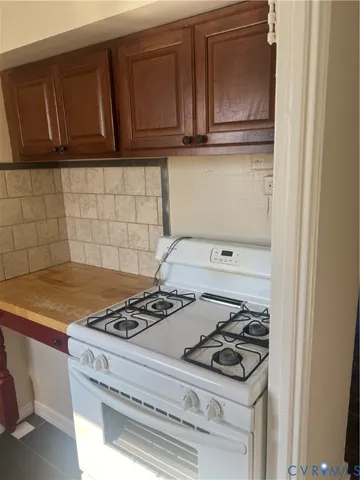 a kitchen with granite countertop a stove and a wooden cabinets