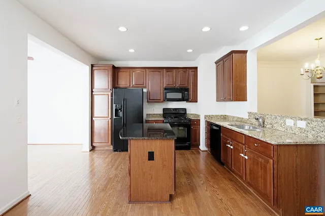 a kitchen with granite countertop a refrigerator stove top oven and sink