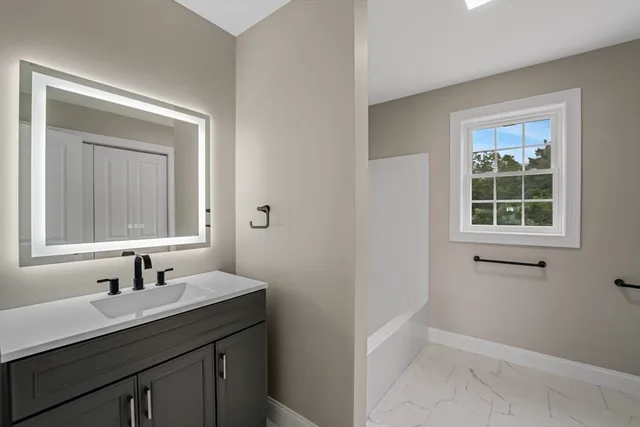 a bathroom with a granite countertop sink a mirror and a window