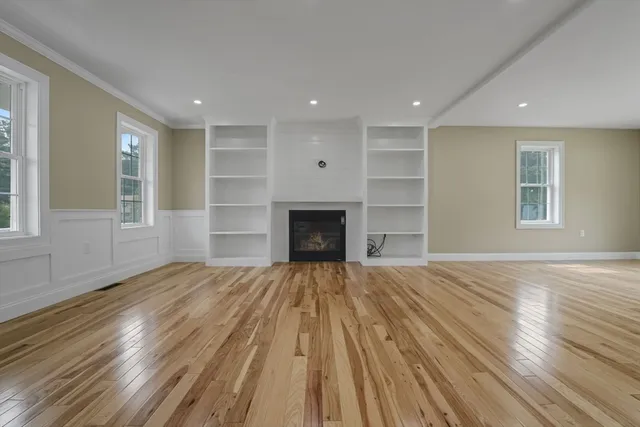 an empty room with wooden floor fireplace and windows