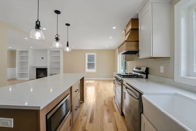 a kitchen with stainless steel appliances granite countertop a sink a stove and a wooden floors
