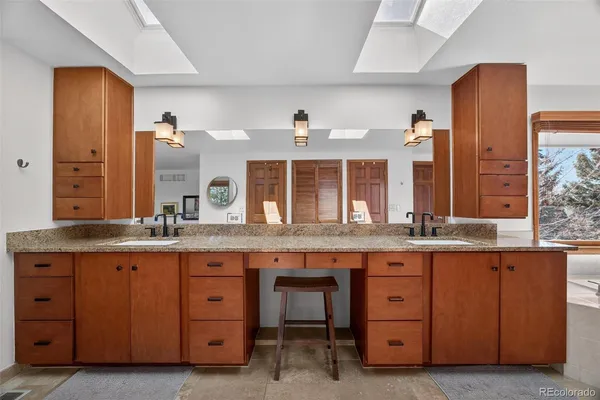 a bathroom with a granite countertop double sink and a large mirror