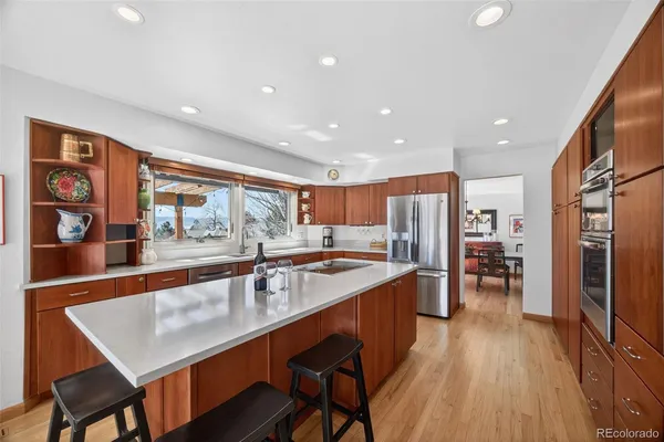 a large kitchen with stainless steel appliances a large counter top a stove a chimney a sink and a refrigerator