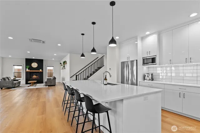 a kitchen with stainless steel appliances kitchen island a refrigerator a stove a sink dishwasher with a dining table and chairs with wooden floor