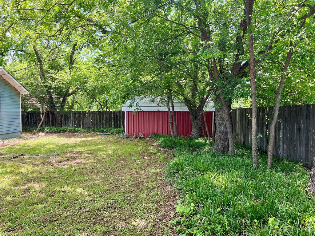 200 Dallas Street Nocona, TX 76255 - Photo 15 of 29 a view of a backyard with large trees and wooden fence