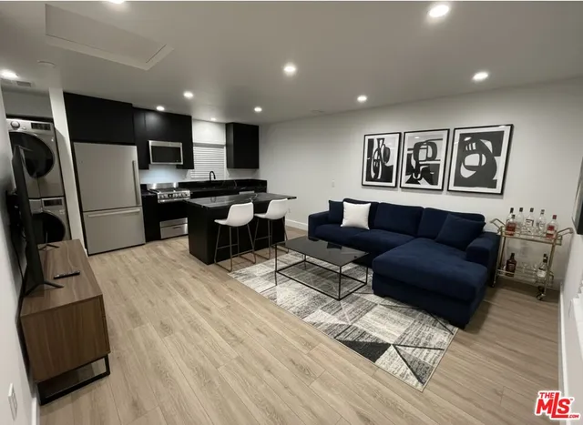 a living room with furniture a large window and wooden floor