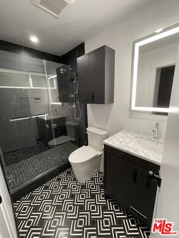a bathroom with a granite countertop toilet and a shower