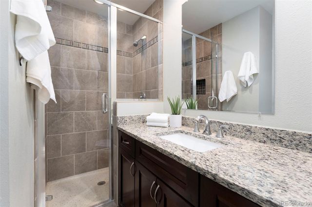 a bathroom with a granite countertop sink a mirror and shower