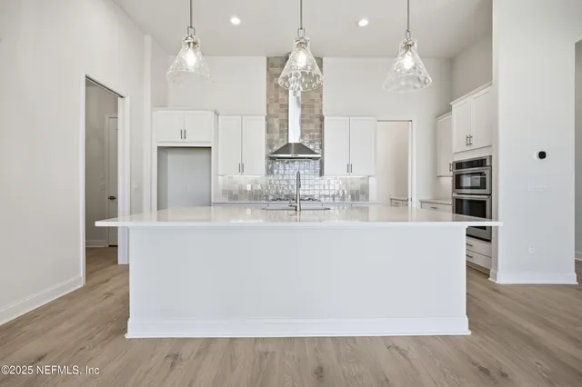 a large kitchen with stainless steel appliances a large counter top a sink a refrigerator and a fireplace