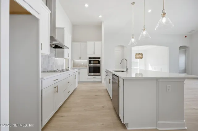 a large kitchen with granite countertop a large counter top appliances and cabinets