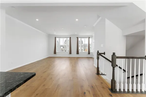 a view of an empty room with wooden floor and windows
