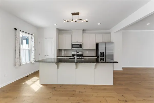 a view of a kitchen with kitchen island a sink wooden floor and counter top space