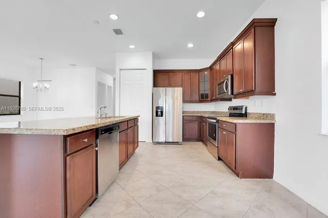 a large kitchen with stainless steel appliances a large counter top and a refrigerator