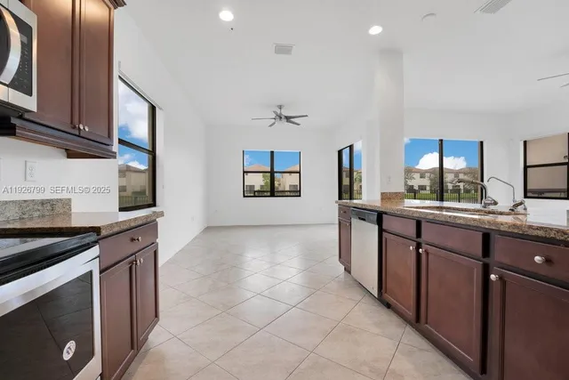 a large kitchen with stainless steel appliances kitchen island granite countertop a large counter top and a stove top oven