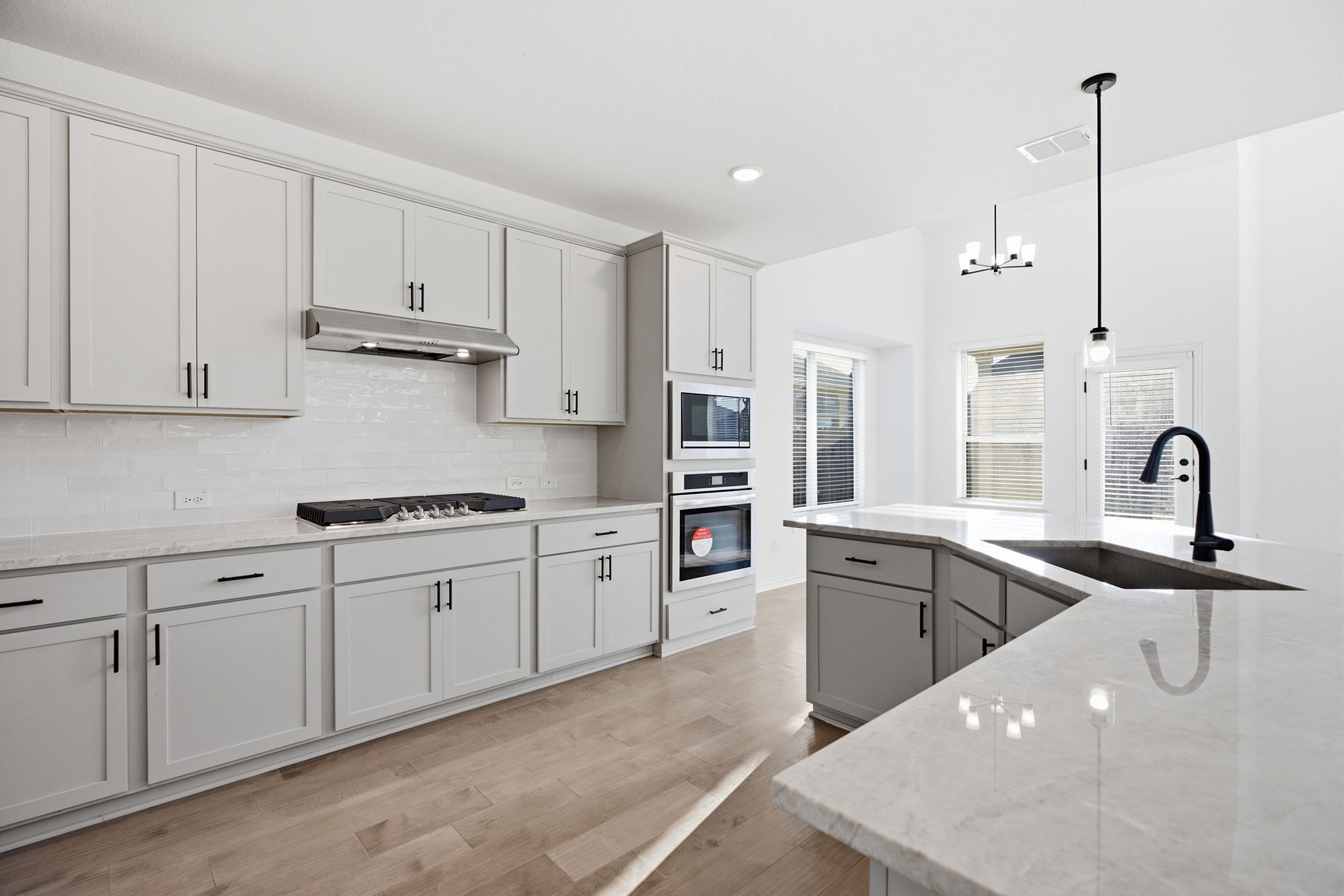 13720 Jon Ryan Road Manor, TX 78653 - Photo 10 of 31 A pristine kitchen features sleek light cabinetry, bright counters, and modern appliances, complemented by a versatile center island with sink.