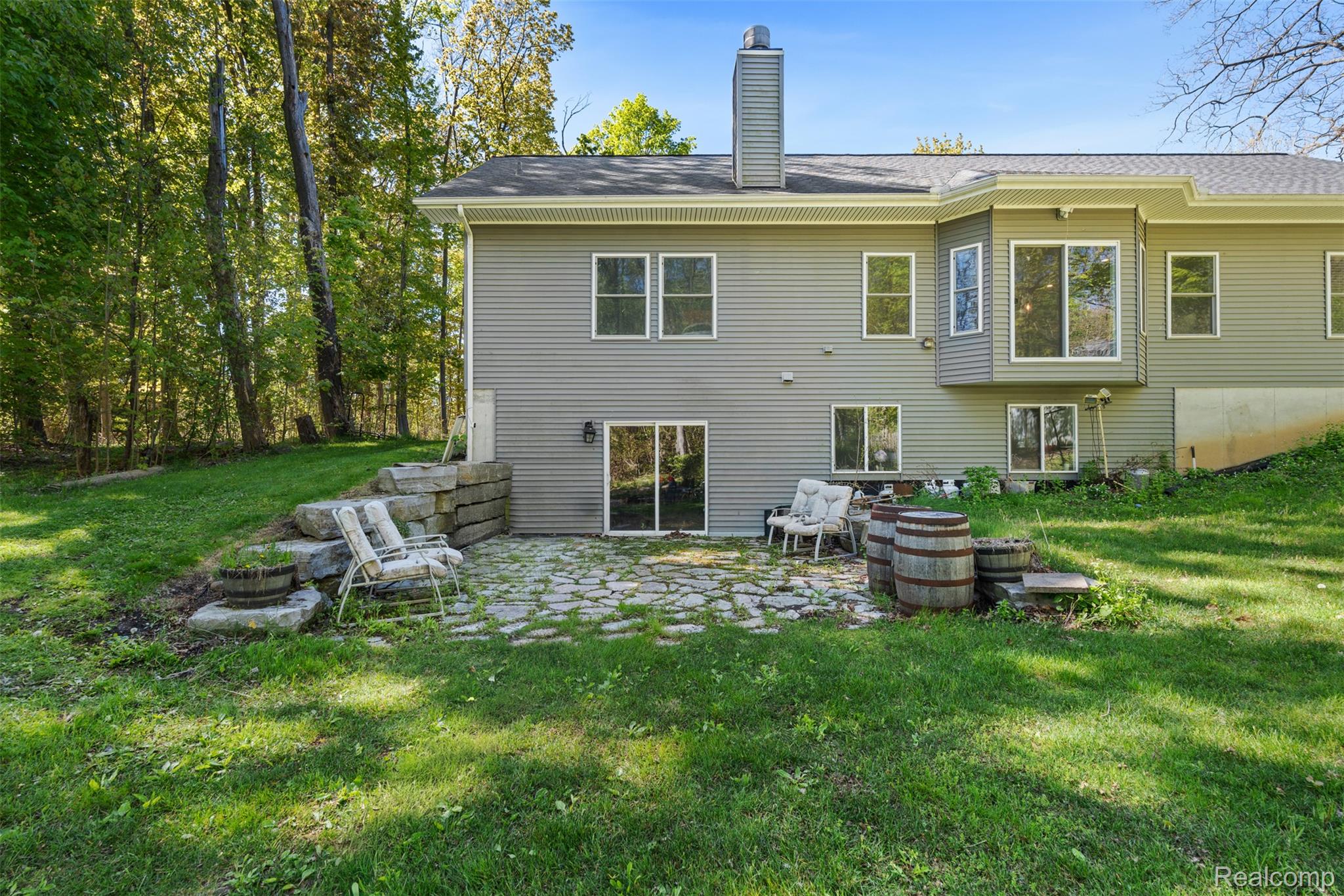 8306 Foster Road Clarkston, MI 48346 - Photo 29 of 38 Rear view of property featuring a chimney, a lawn, a patio, and roof with shingles