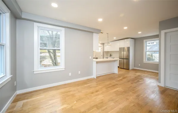 a view of an empty room with a kitchen and a window