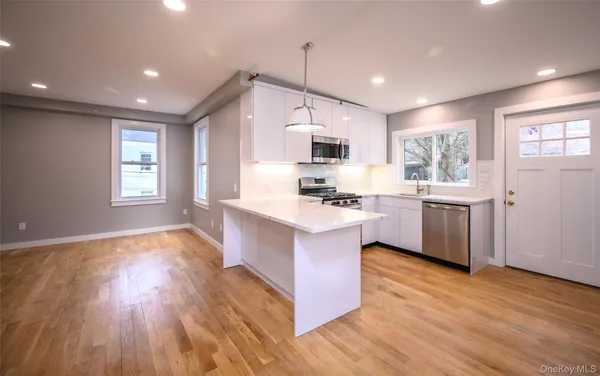 a kitchen with kitchen island granite countertop a sink cabinets and wooden floor