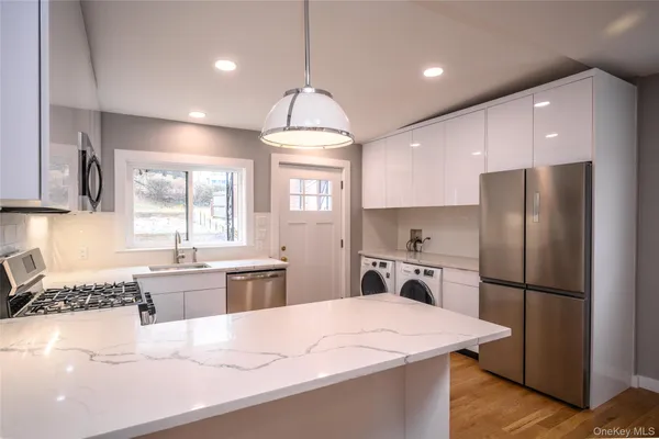 a kitchen with a refrigerator a sink dishwasher a stove and white countertops with wooden floor