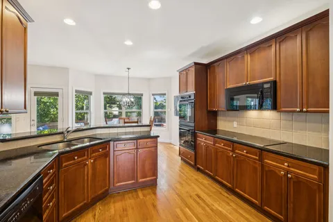 a large kitchen with stainless steel appliances granite countertop wooden cabinets a sink and a stove