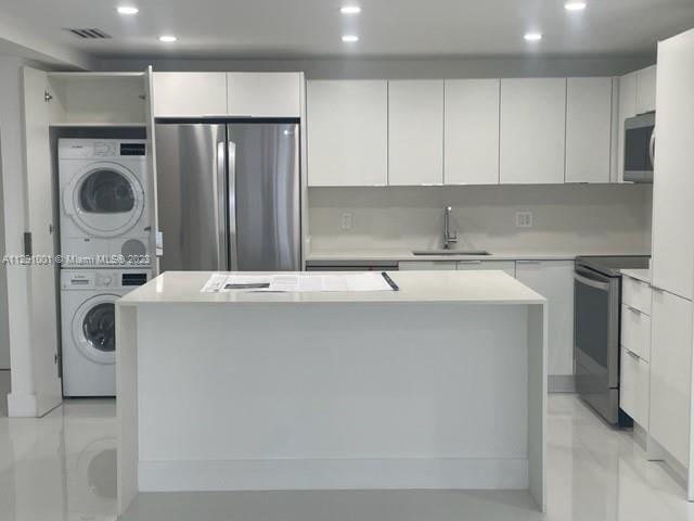 a utility room with stainless steel appliances a sink a washer and dryer