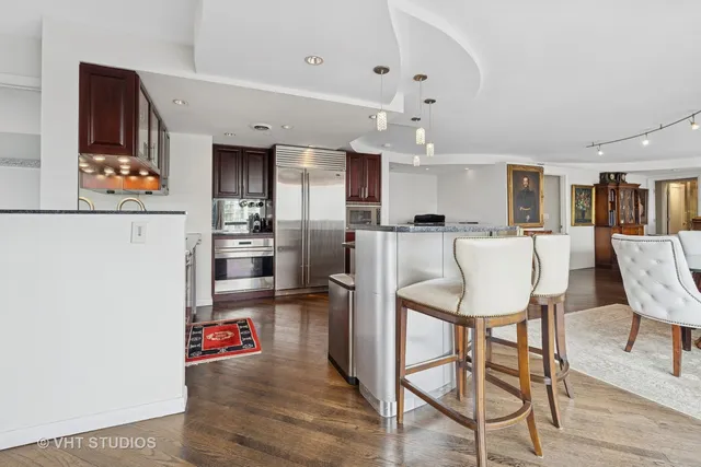 a kitchen with stainless steel appliances refrigerator dining table and chairs