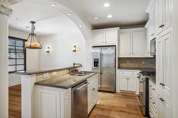 a kitchen that has a sink a refrigerator and cabinets