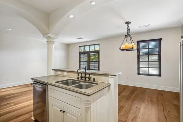 a kitchen that has a sink and a stove with wooden floor