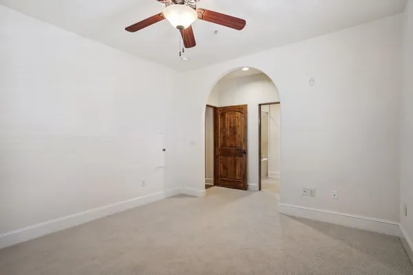 an empty room with a chandelier fan and windows