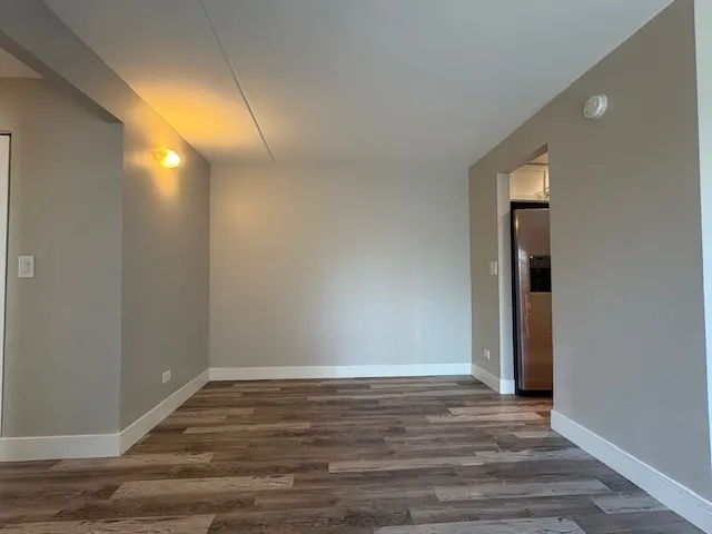 a view of an empty room with wooden floor and closet