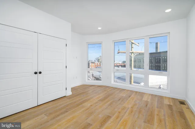 a big room with wooden floor closet and windows