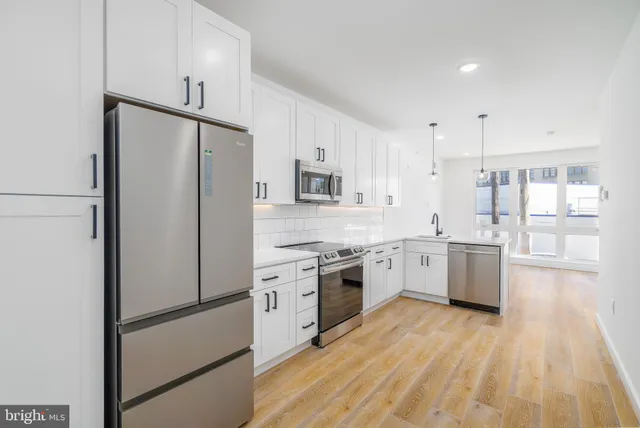 a kitchen with a refrigerator a sink dishwasher a stove and white cabinets with wooden floor