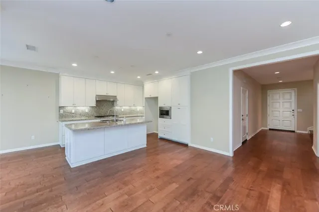 a view of large kitchen with kitchen island sink stainless steel appliances refrigerator stove and cabinets