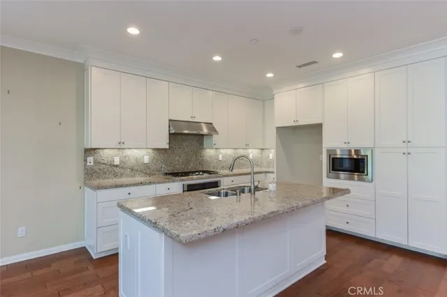 a kitchen with stainless steel appliances granite countertop a sink a stove and a refrigerator