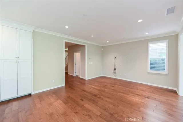 a view of an empty room with wooden floor and window