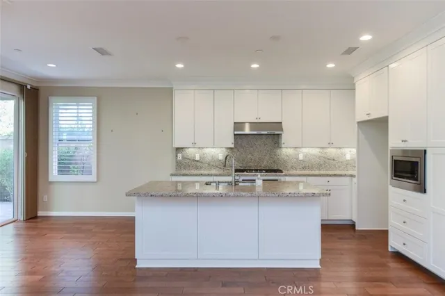 a kitchen with stainless steel appliances granite countertop a sink a stove a microwave a refrigerator and cabinets