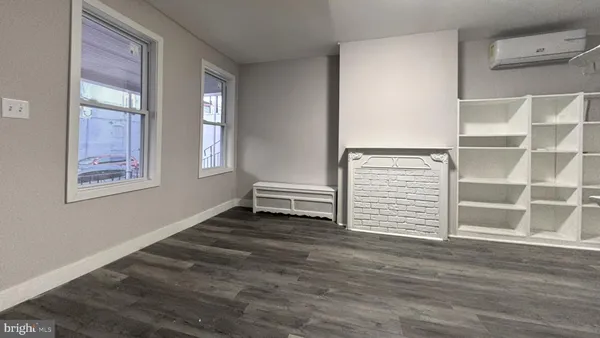 a view of an empty room with wooden floor and windows