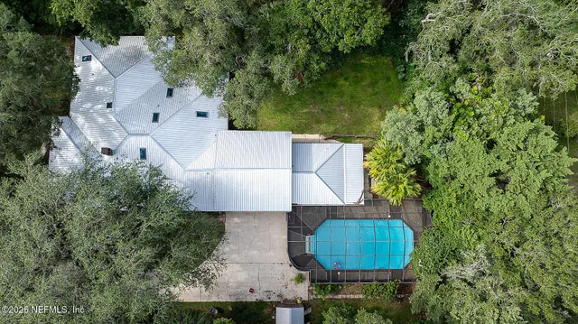 an aerial view of a house with swimming pool and large trees