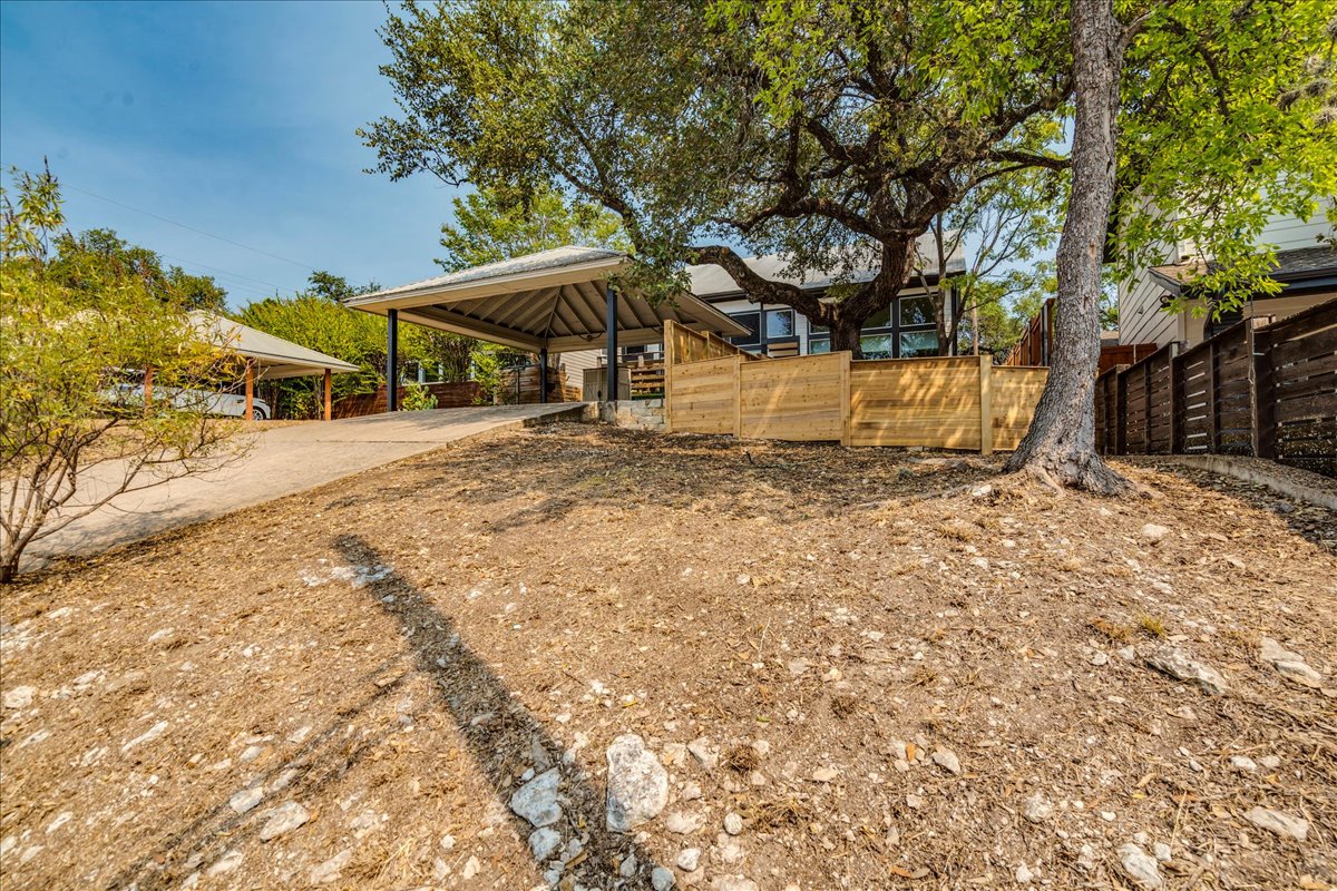 2811 Hardeman Street, Unit B Austin, TX 78704 - Photo 29 of 34 Mature trees shade a sloped yard leading up to a covered carport structure.