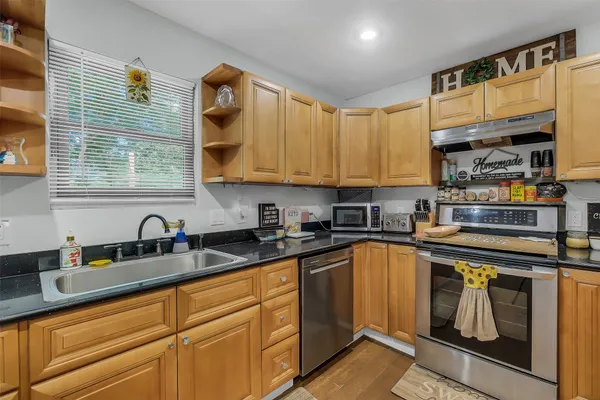 a kitchen with granite countertop a sink a stove and cabinets
