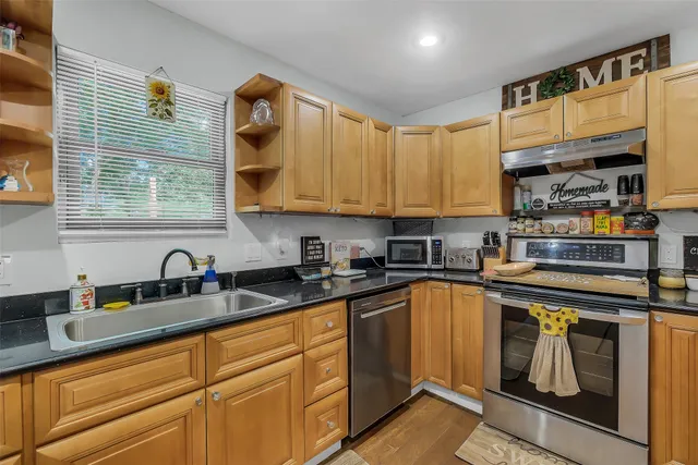 a kitchen with granite countertop a sink a stove and cabinets