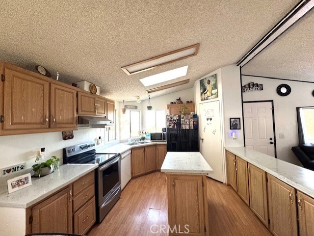 24425 Woolsey Canyon Road, Unit 196 West Hills, CA 91304 - Photo 18 of 29 a large kitchen with stainless steel appliances lots of counter space and wooden floor