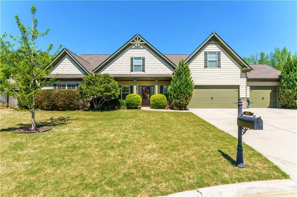 a front view of house with yard and trees in the background