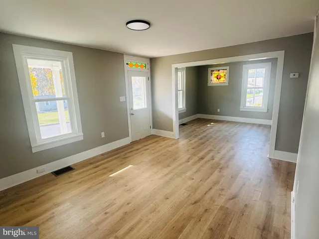 a view of an empty room with window and wooden floor